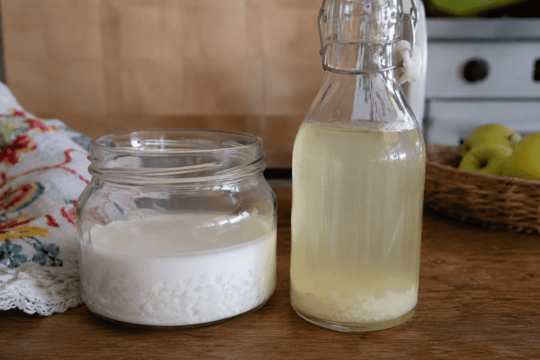 Melkkefir en waterkefir in glazen potten op houten tafel in een natuurlijke keukenomgeving